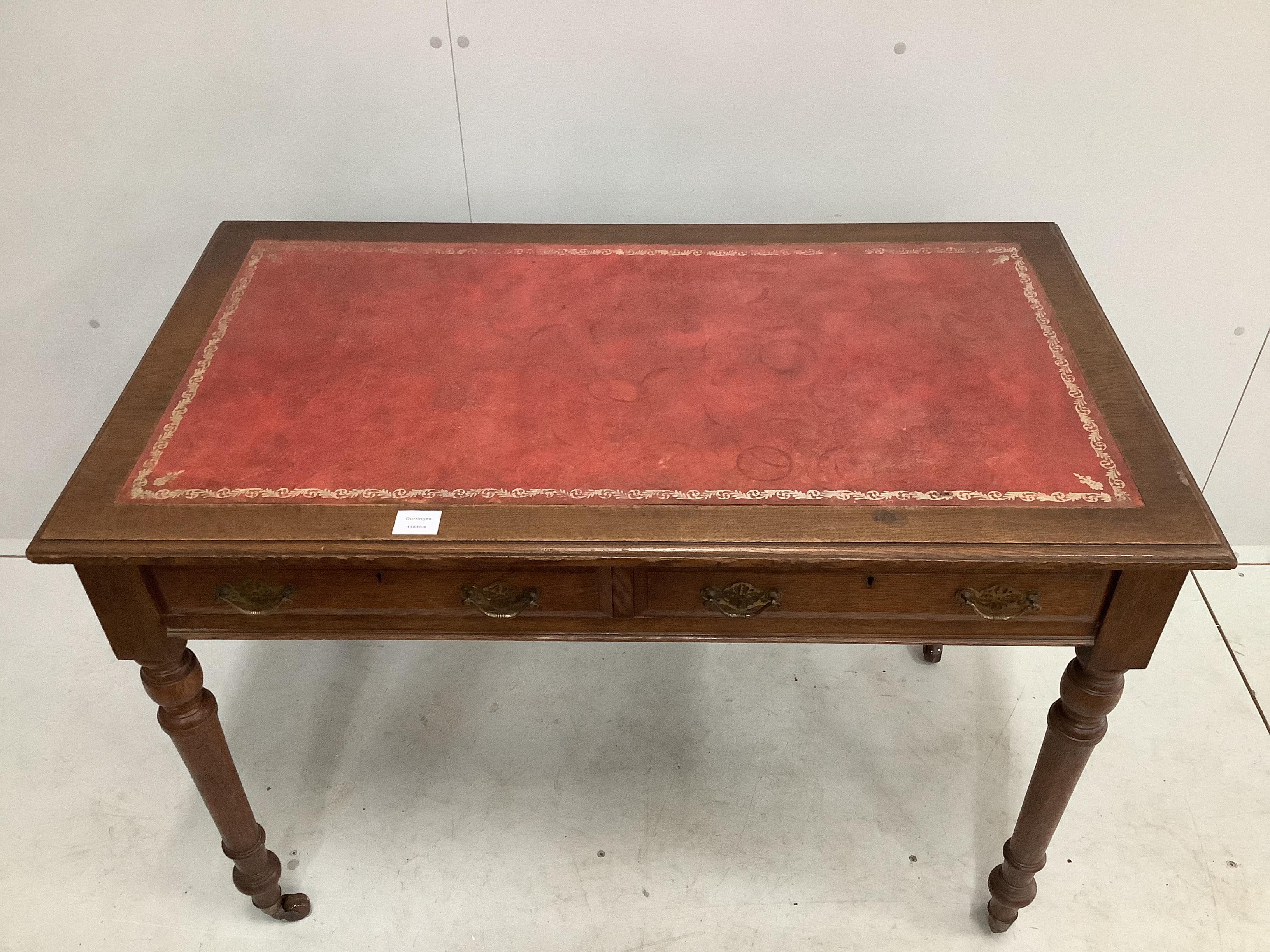 A late Victorian oak two drawer writing table, with red leather inset top, width 106cm, depth 60cm, height 76cm